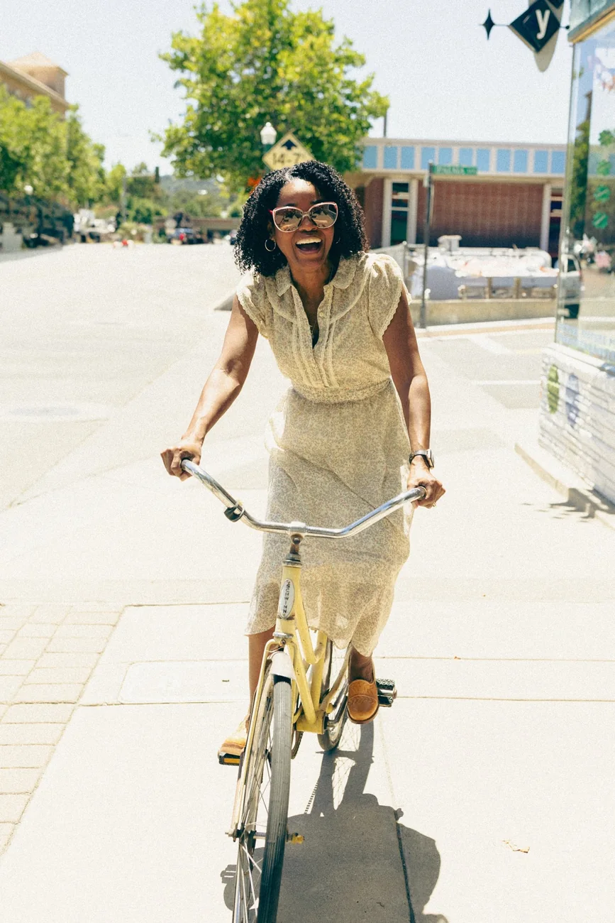 Shante riding a bicycle in a light summer dress